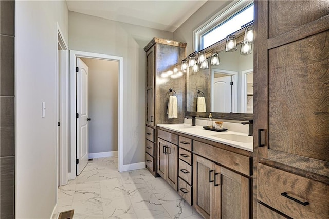 full bath with marble finish floor, a sink, double vanity, and baseboards