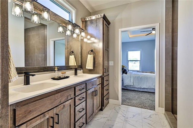 ensuite bathroom with ensuite bathroom, marble finish floor, a sink, and baseboards