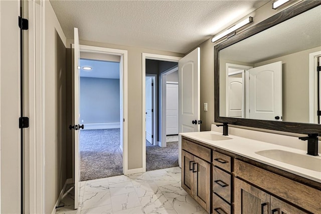 full bathroom featuring marble finish floor, double vanity, a sink, and a textured ceiling