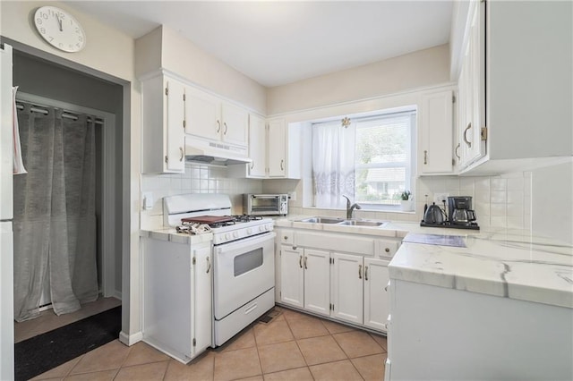 kitchen featuring white range with gas stovetop, sink, white cabinets, and light tile patterned floors