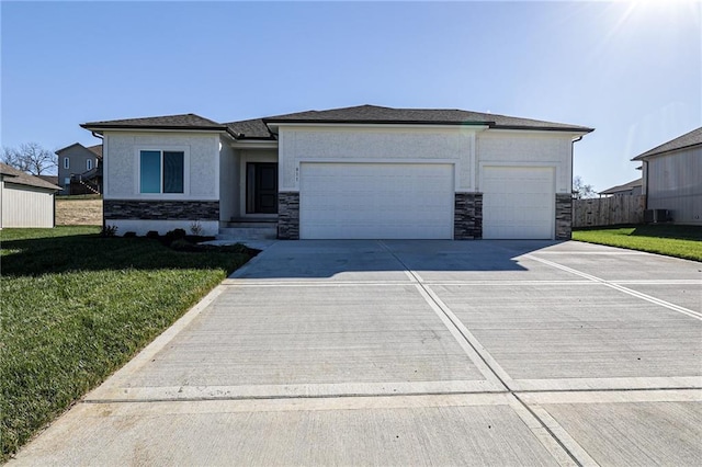 prairie-style house with a front yard, driveway, an attached garage, stucco siding, and stone siding