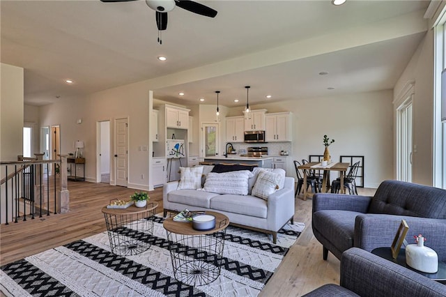 living room featuring light hardwood / wood-style flooring, ceiling fan, and sink