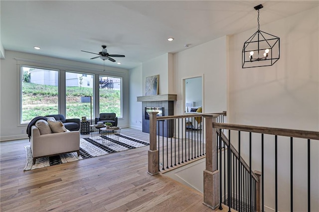 living area with recessed lighting, ceiling fan with notable chandelier, baseboards, and wood finished floors