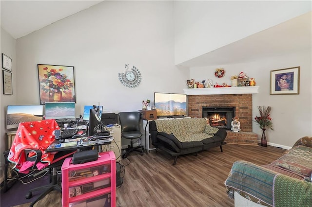 living room with wood-type flooring, vaulted ceiling, and a brick fireplace