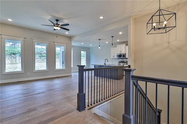 interior space with ceiling fan with notable chandelier, hardwood / wood-style flooring, and sink