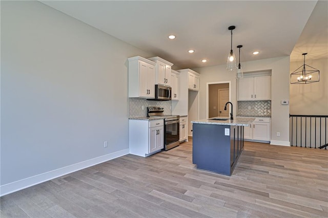 kitchen featuring hanging light fixtures, a kitchen island with sink, white cabinetry, and stainless steel appliances