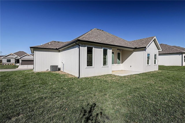 rear view of house with a lawn, a garage, central air condition unit, and a patio