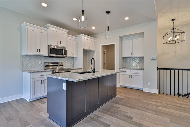 kitchen featuring white cabinetry, an inviting chandelier, a sink, light wood-style flooring, and appliances with stainless steel finishes