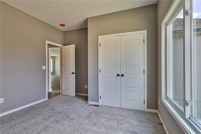 unfurnished bedroom with multiple windows, a closet, baseboards, and carpet