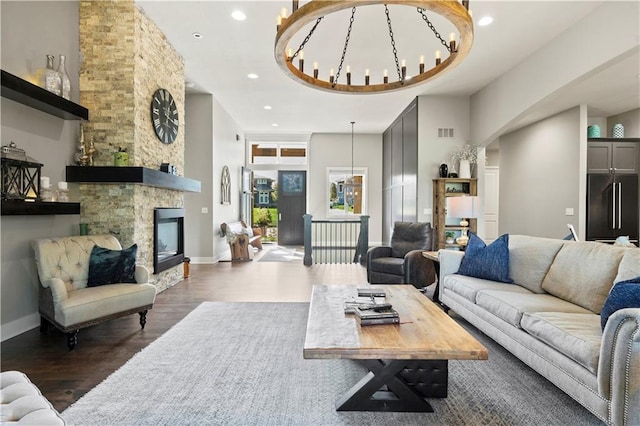 living room with a notable chandelier, a towering ceiling, dark hardwood / wood-style flooring, and a fireplace