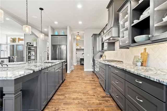 kitchen with gray cabinetry, sink, hanging light fixtures, hardwood / wood-style flooring, and decorative backsplash