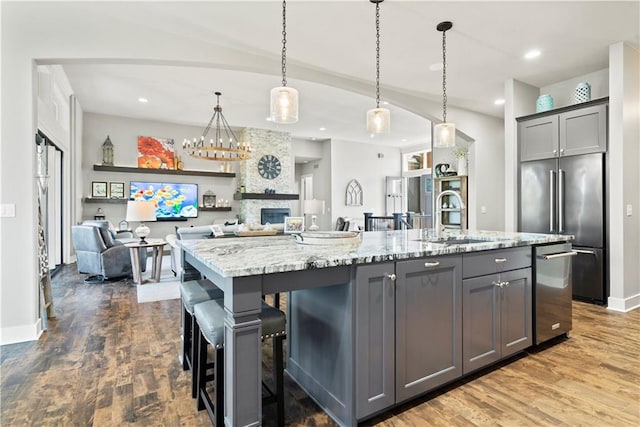 kitchen featuring a large island with sink, sink, pendant lighting, and gray cabinets