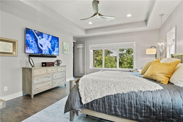 bedroom with ceiling fan, a raised ceiling, and dark hardwood / wood-style flooring