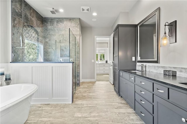 bathroom with vanity, independent shower and bath, and hardwood / wood-style floors