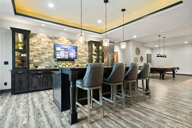 bar with billiards, high end refrigerator, hanging light fixtures, a tray ceiling, and wood-type flooring