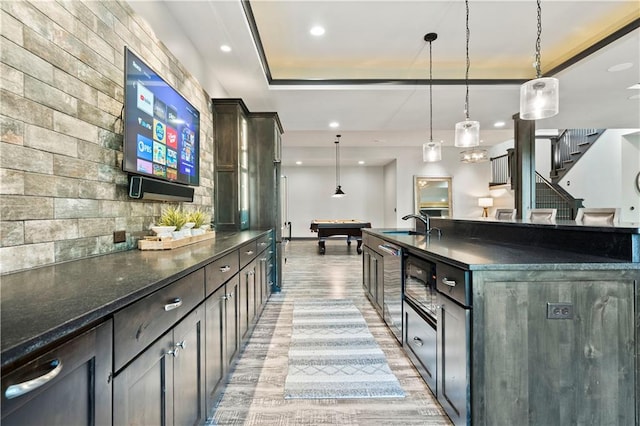 kitchen featuring light wood-type flooring, pool table, a spacious island, dark brown cabinets, and decorative light fixtures