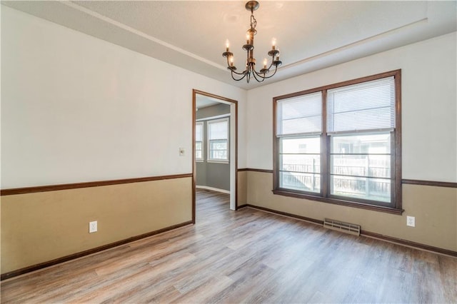 unfurnished room with an inviting chandelier, hardwood / wood-style flooring, and a tray ceiling