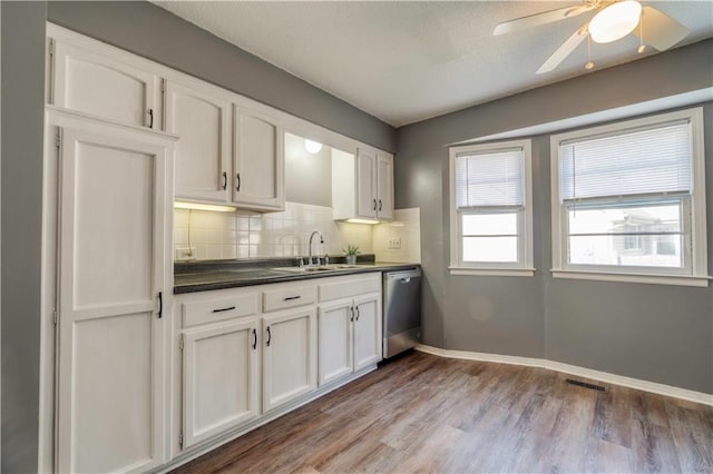 kitchen with sink, white cabinetry, tasteful backsplash, stainless steel dishwasher, and light wood-type flooring