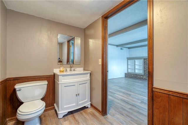 bathroom with hardwood / wood-style flooring, vanity, toilet, and wood walls