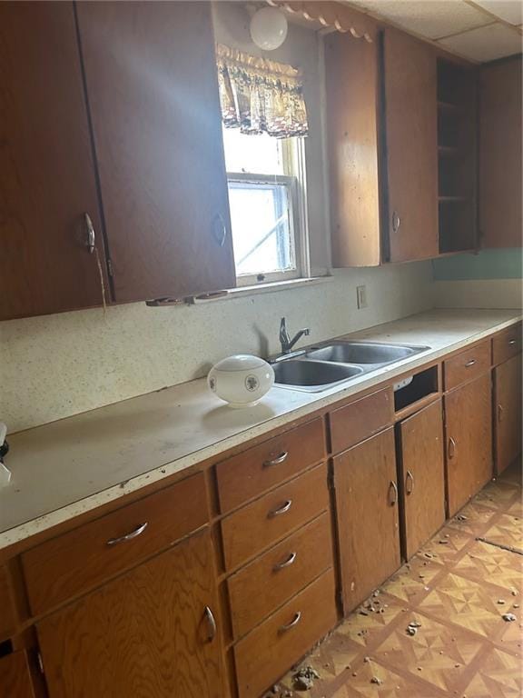 kitchen featuring brown cabinetry, light countertops, a sink, and light floors