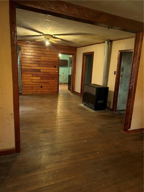 interior space featuring baseboards, beamed ceiling, hardwood / wood-style flooring, and wooden walls