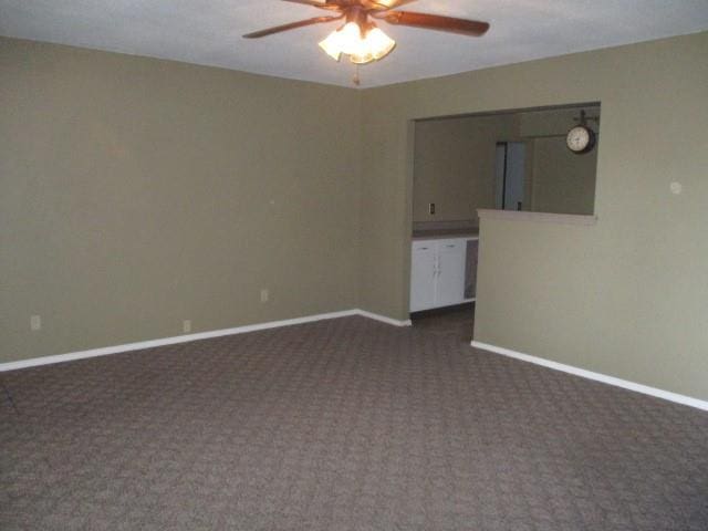 spare room with dark carpet and ceiling fan