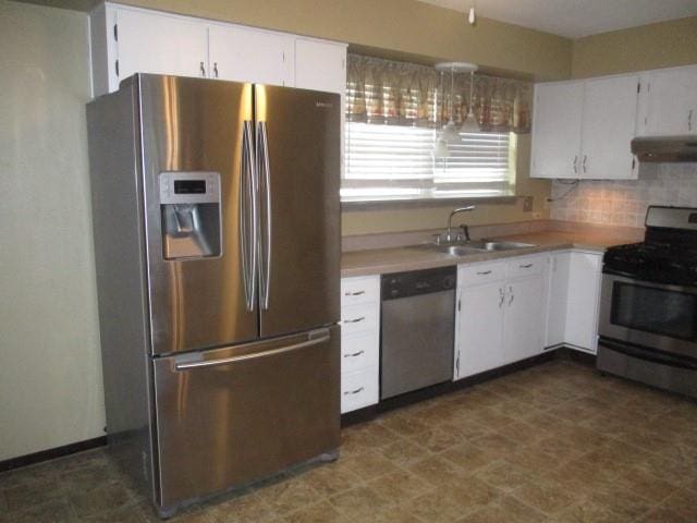 kitchen featuring exhaust hood, white cabinetry, appliances with stainless steel finishes, and tasteful backsplash