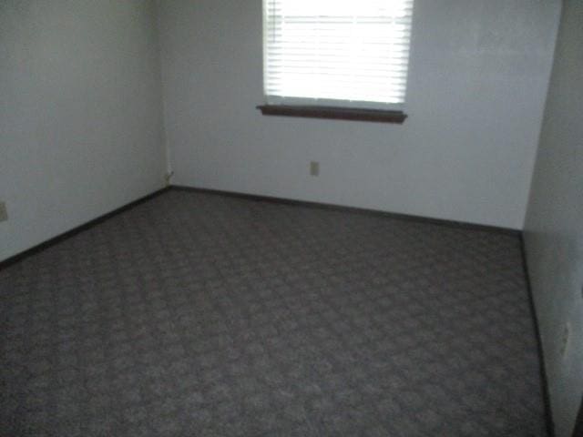 unfurnished room featuring dark carpet