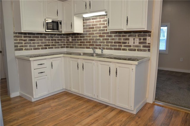 kitchen featuring sink, stainless steel microwave, and white cabinets