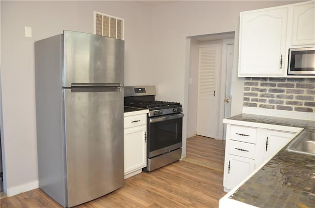 kitchen with white cabinetry, stainless steel appliances, and light hardwood / wood-style floors