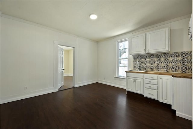 kitchen featuring white cabinets, dark hardwood / wood-style floors, crown molding, and sink