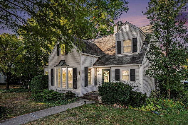 cape cod house featuring a lawn