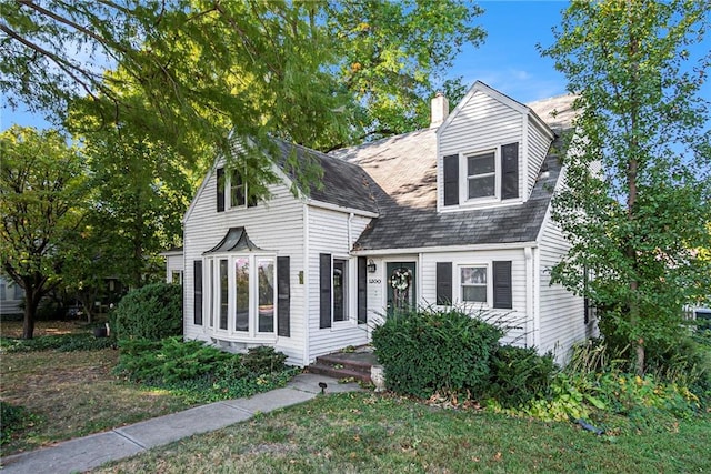 cape cod home featuring a front yard