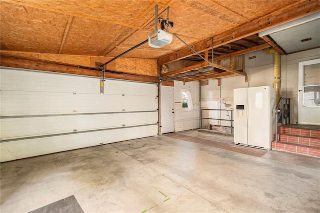 garage with a garage door opener and white refrigerator with ice dispenser