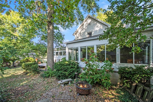 rear view of property featuring a sunroom and a fire pit