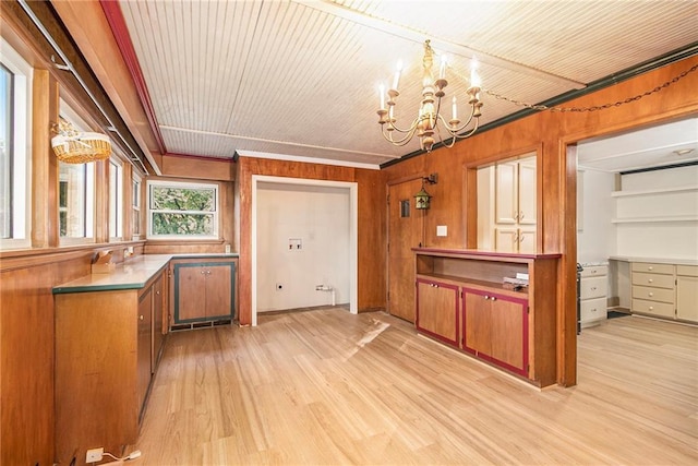 kitchen with a notable chandelier, decorative light fixtures, wooden walls, and light hardwood / wood-style floors