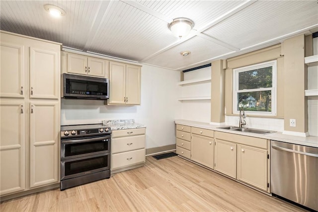 kitchen with appliances with stainless steel finishes, sink, light hardwood / wood-style flooring, and cream cabinetry