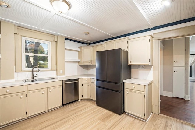 kitchen with sink, black fridge, light hardwood / wood-style flooring, dishwasher, and cream cabinetry