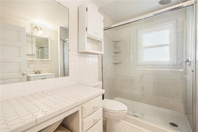 bathroom featuring tile walls, decorative backsplash, vanity, toilet, and a shower with door