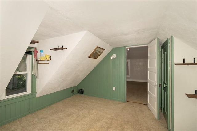 additional living space featuring vaulted ceiling and light carpet