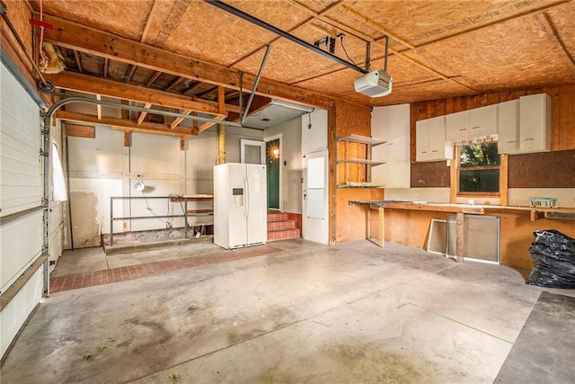 garage featuring a garage door opener and white fridge with ice dispenser