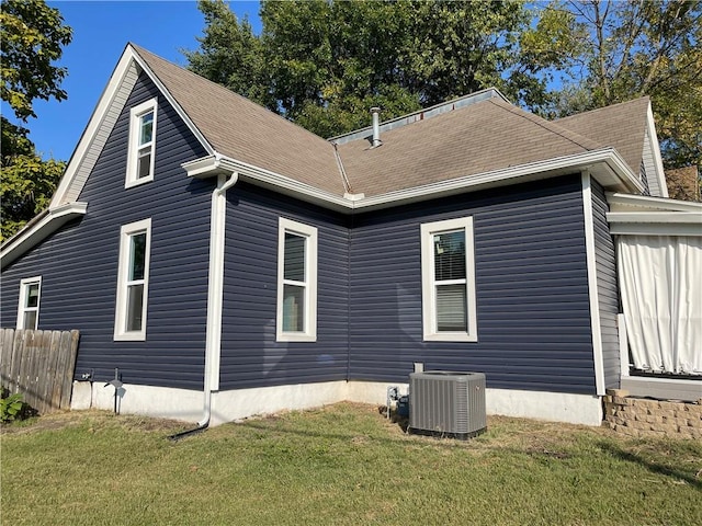 view of side of property with central air condition unit and a yard