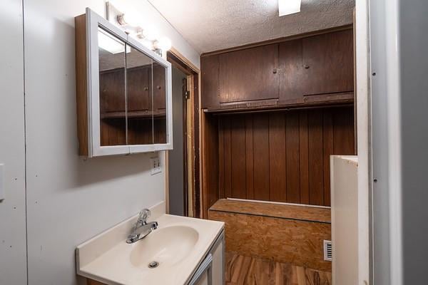 bathroom with wooden walls, vanity, wood-type flooring, and a textured ceiling