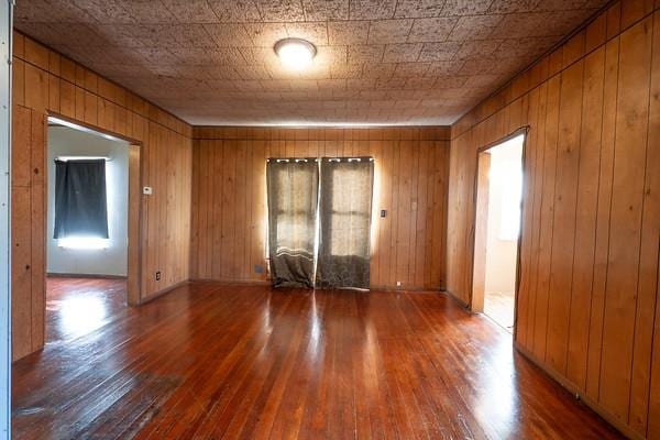 unfurnished room with plenty of natural light, wood walls, and hardwood / wood-style floors