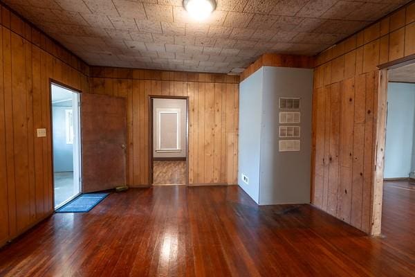 empty room with wood walls and dark wood-type flooring