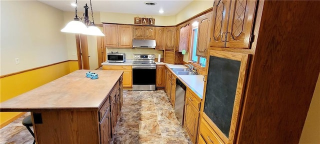 1516 E Lincoln St, Iola, KS 66749 - kitchen with stainless steel appliances, extractor fan, a kitchen island, light countertops, and pendant lighting