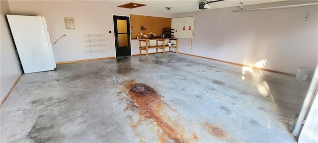 1516 E Lincoln St, Iola, KS 66749 - garage with a garage door opener, baseboards, and freestanding refrigerator