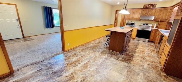 kitchen with a center island, light countertops, appliances with stainless steel finishes, light carpet, and under cabinet range hood