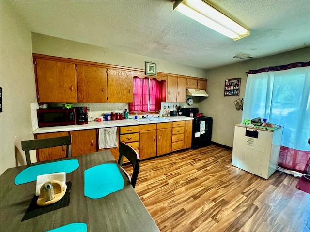 kitchen featuring a textured ceiling, black appliances, sink, light hardwood / wood-style floors, and backsplash