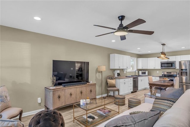 living room with light hardwood / wood-style floors, sink, and ceiling fan